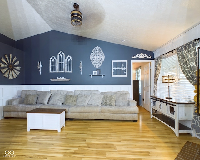 living room with wood-type flooring, a textured ceiling, and vaulted ceiling