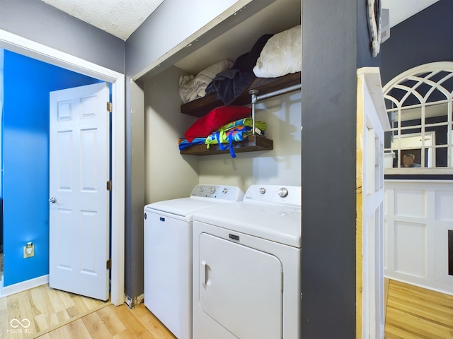 washroom featuring light hardwood / wood-style floors, a textured ceiling, and independent washer and dryer