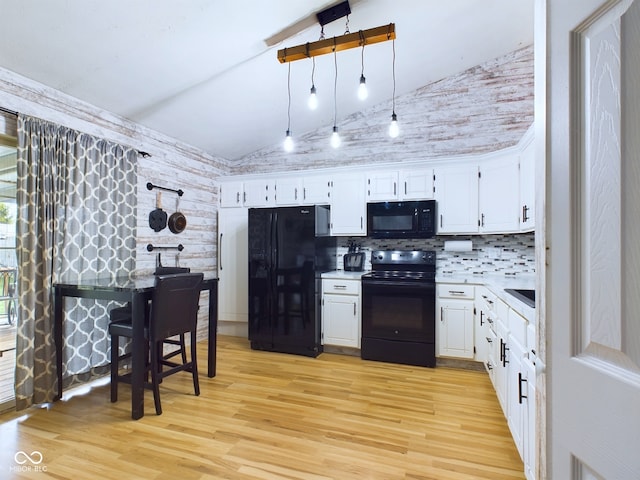 kitchen featuring white cabinetry, pendant lighting, lofted ceiling, light hardwood / wood-style floors, and black appliances