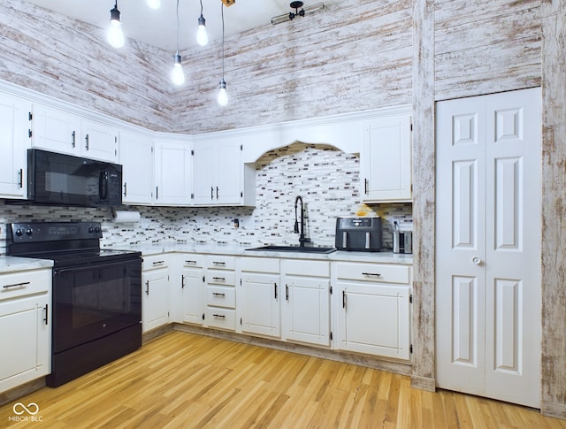 kitchen featuring white cabinets, a towering ceiling, black appliances, and decorative light fixtures