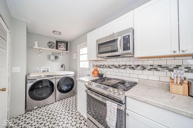 kitchen with white cabinets, light stone countertops, separate washer and dryer, appliances with stainless steel finishes, and tasteful backsplash