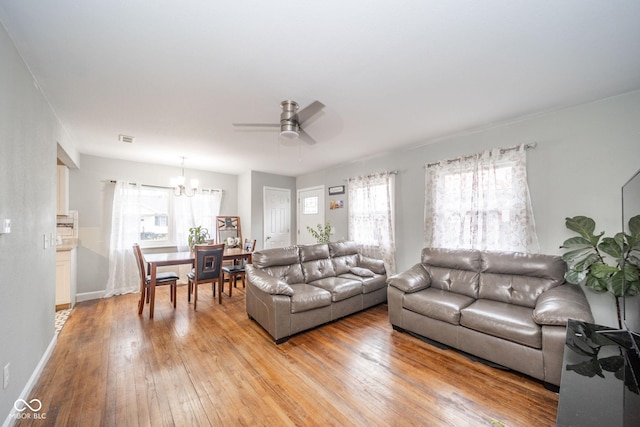 living room featuring ceiling fan with notable chandelier, light hardwood / wood-style floors, and a wealth of natural light