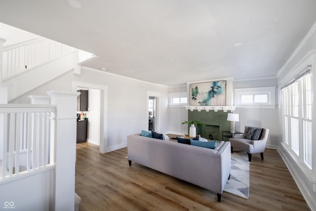 living room featuring hardwood / wood-style flooring, ornamental molding, and a brick fireplace