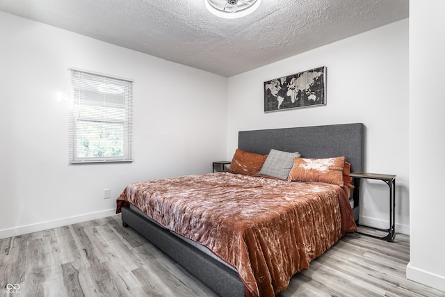 bedroom featuring light hardwood / wood-style floors and a textured ceiling