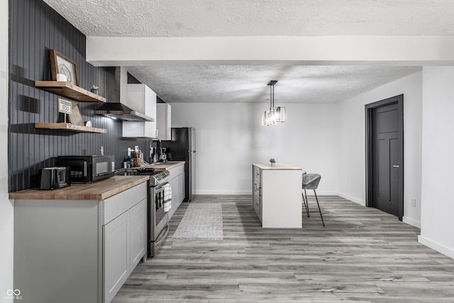 kitchen with wooden counters, a breakfast bar area, light hardwood / wood-style flooring, decorative light fixtures, and stainless steel appliances