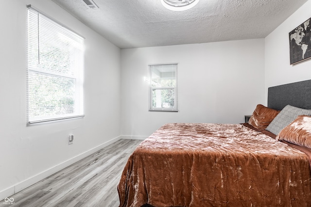 bedroom with a textured ceiling and light hardwood / wood-style flooring