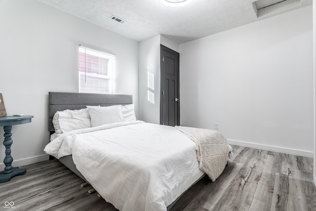 bedroom with wood-type flooring and a textured ceiling