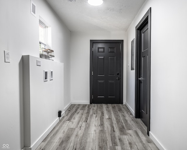 doorway to outside featuring a textured ceiling and light hardwood / wood-style floors