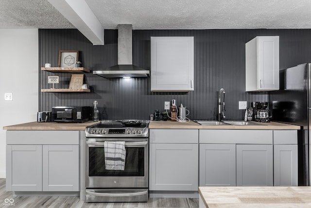 kitchen with wall chimney exhaust hood, a textured ceiling, sink, black appliances, and light hardwood / wood-style floors