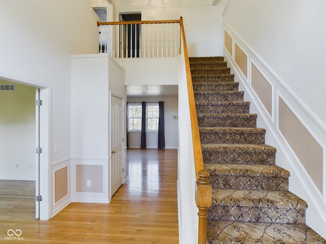 staircase with wood-type flooring and a high ceiling