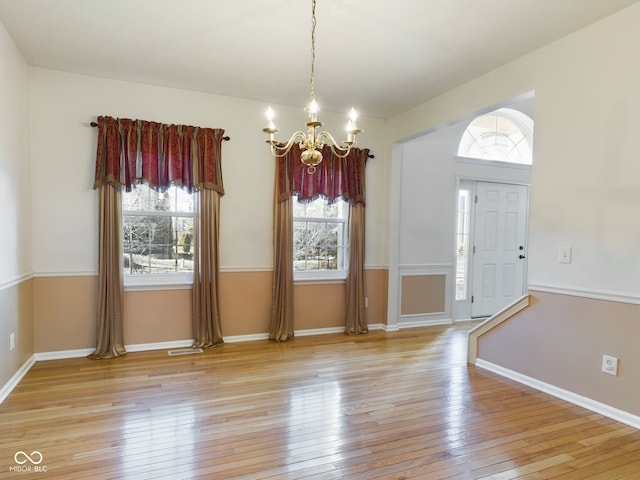 unfurnished dining area featuring a wealth of natural light, a chandelier, and light wood-type flooring