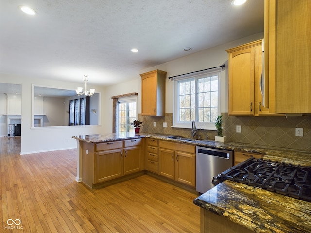 kitchen featuring dishwasher, sink, light wood-type flooring, kitchen peninsula, and a chandelier