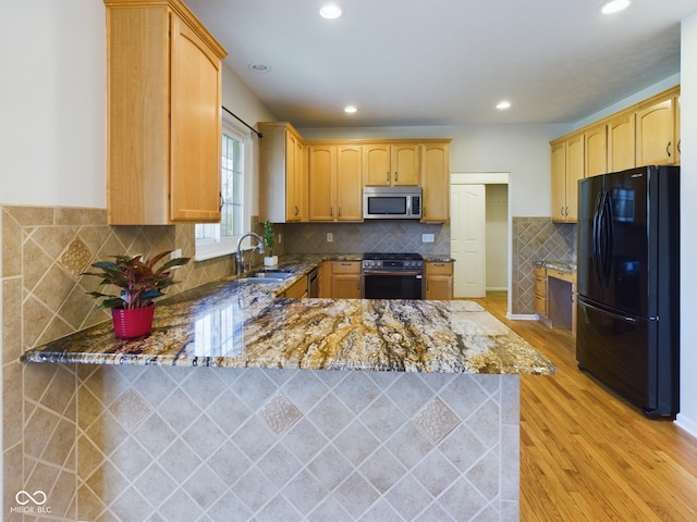 kitchen featuring sink, appliances with stainless steel finishes, light hardwood / wood-style floors, light stone counters, and kitchen peninsula