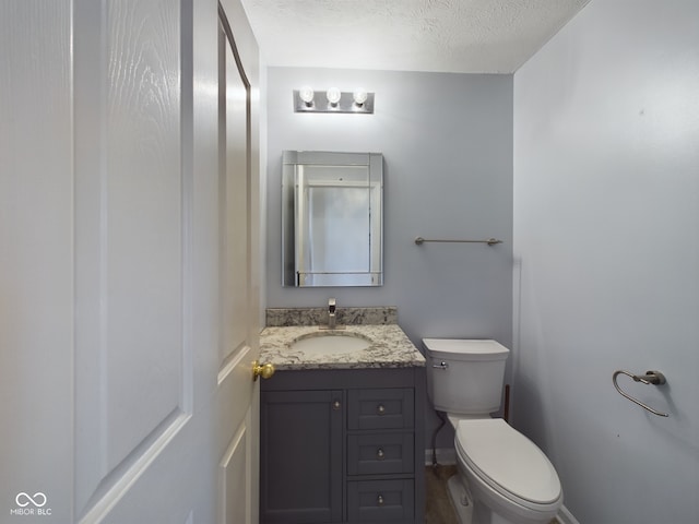 bathroom featuring vanity, a textured ceiling, and toilet