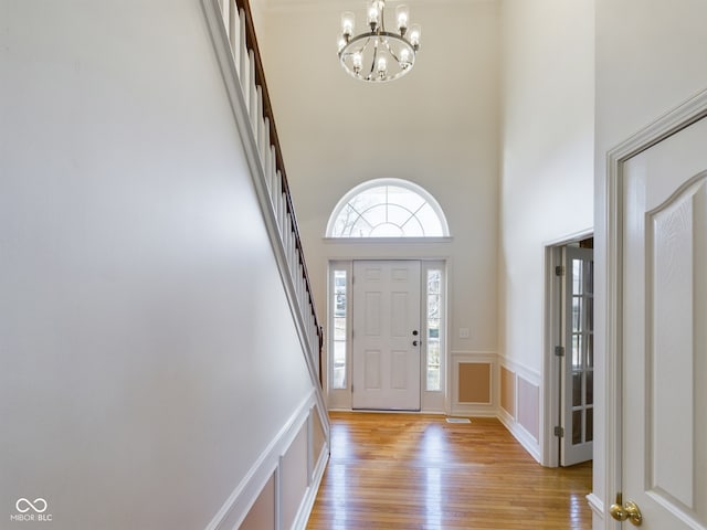 foyer entrance featuring a high ceiling, light wood-type flooring, and a notable chandelier