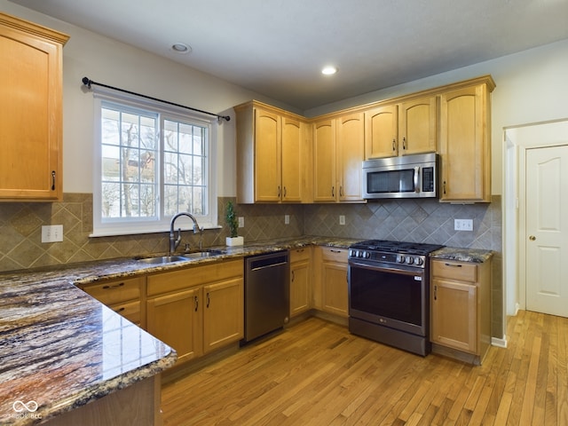 kitchen with dark stone counters, sink, light hardwood / wood-style flooring, decorative backsplash, and stainless steel appliances