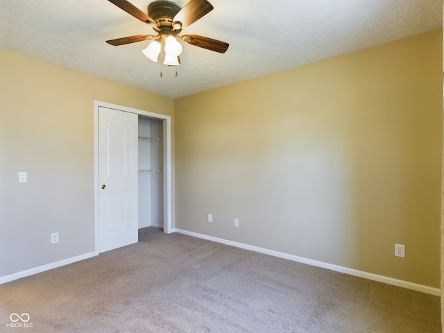 unfurnished bedroom featuring carpet flooring, ceiling fan, a closet, and a textured ceiling