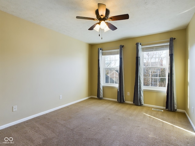 unfurnished room featuring ceiling fan, light colored carpet, and a textured ceiling