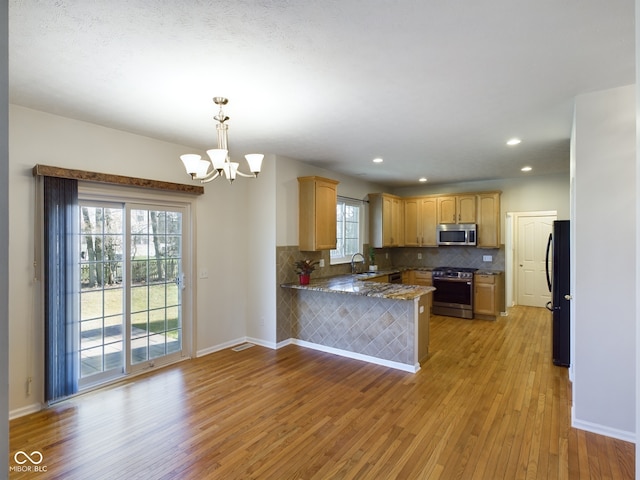 kitchen with kitchen peninsula, appliances with stainless steel finishes, light hardwood / wood-style flooring, and a wealth of natural light