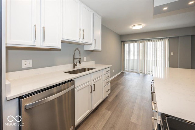 kitchen featuring sink, stainless steel dishwasher, light stone countertops, light wood-type flooring, and white cabinetry