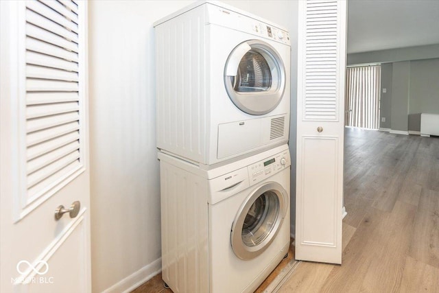 laundry area with light hardwood / wood-style floors and stacked washer and clothes dryer