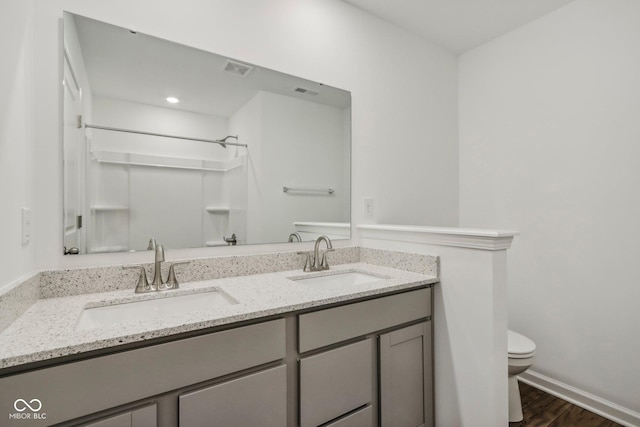 bathroom with a shower, hardwood / wood-style floors, vanity, and toilet