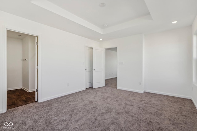 unfurnished bedroom with carpet flooring and a tray ceiling