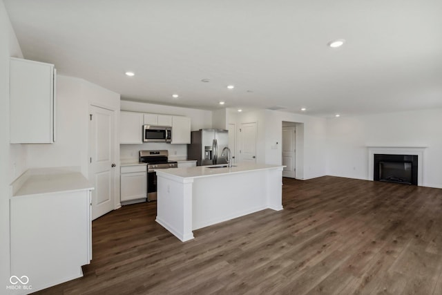 kitchen with white cabinetry, sink, dark wood-type flooring, stainless steel appliances, and a center island with sink