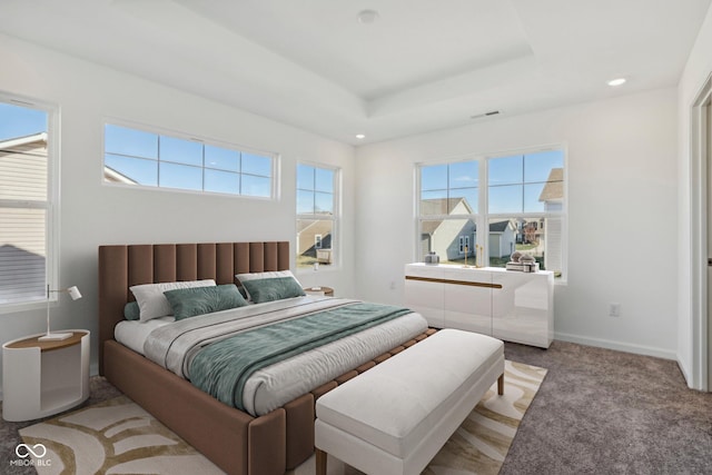 bedroom with a raised ceiling and light colored carpet