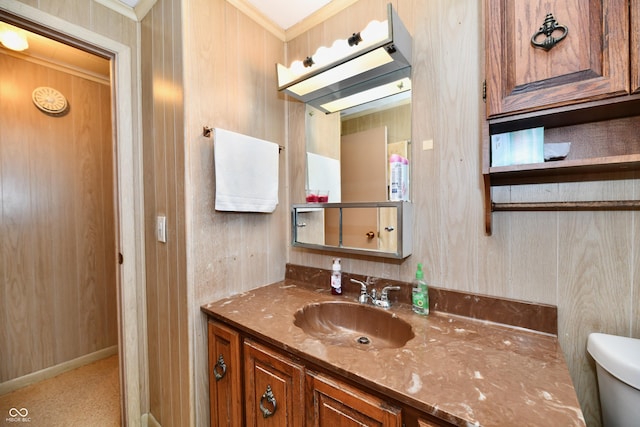 bathroom with vanity, toilet, crown molding, and wooden walls