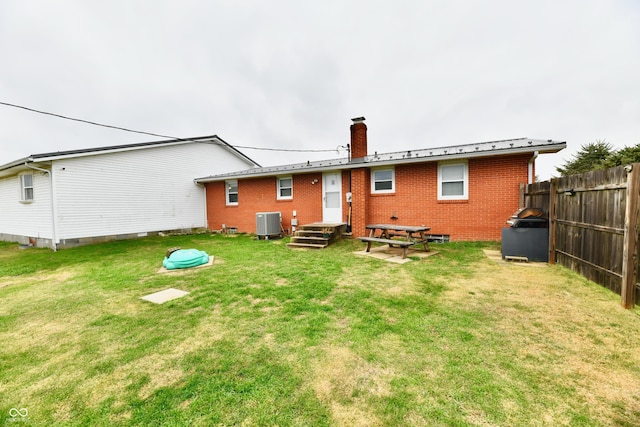 back of house featuring central AC unit and a lawn