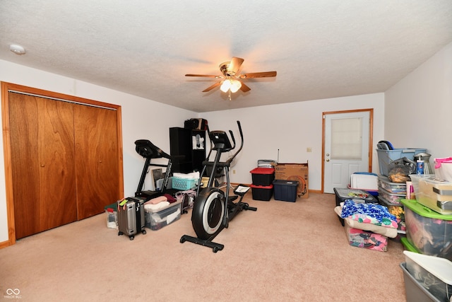 workout area featuring ceiling fan, carpet floors, and a textured ceiling