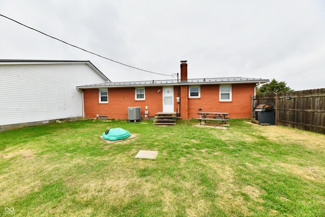 rear view of house featuring a yard and central AC