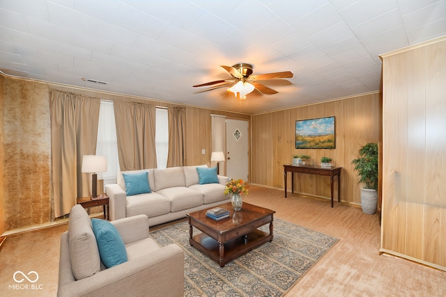 living room with ceiling fan, light colored carpet, and wooden walls