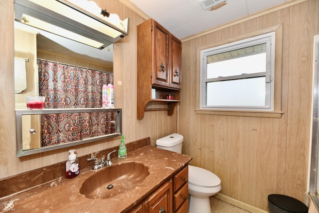 bathroom featuring vanity, toilet, and wood walls