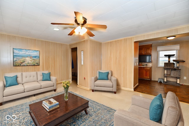 living room with ceiling fan, wood walls, and crown molding