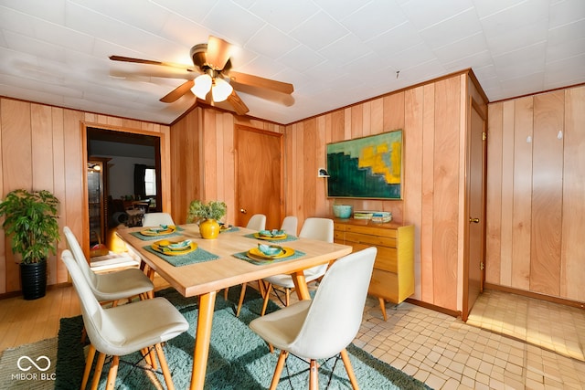 dining room featuring wood walls, light hardwood / wood-style flooring, and ceiling fan