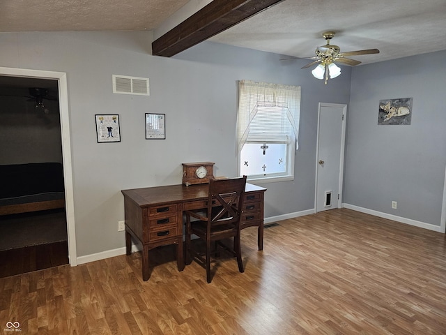 home office with ceiling fan, hardwood / wood-style floors, beamed ceiling, and a textured ceiling