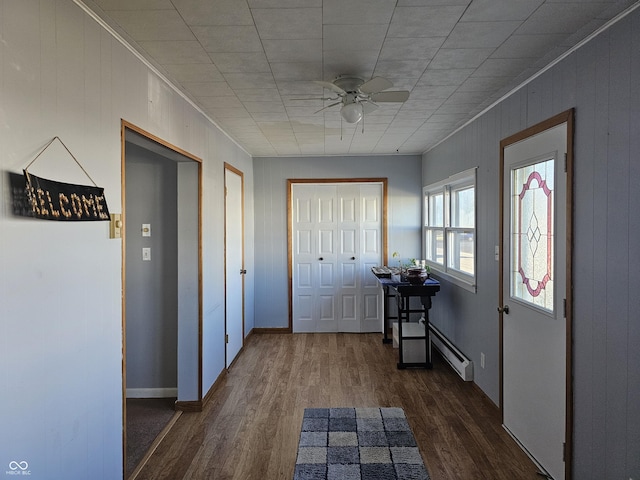 foyer entrance featuring dark hardwood / wood-style floors, ceiling fan, crown molding, and a baseboard heating unit