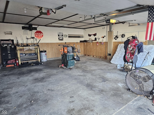 garage with a workshop area, wooden walls, and a garage door opener