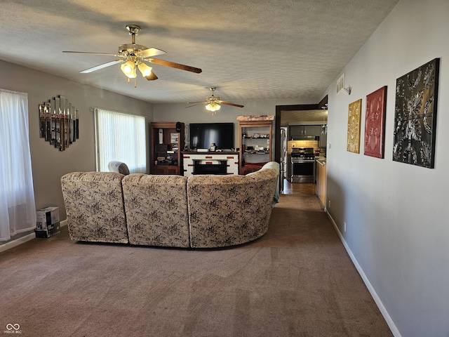 carpeted living room featuring ceiling fan and a textured ceiling