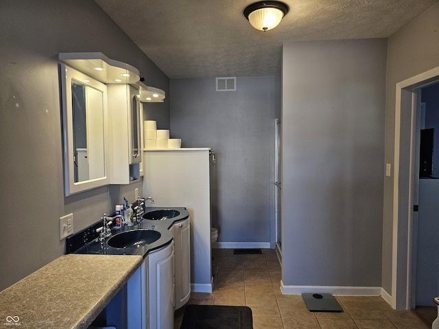 kitchen with a textured ceiling, light tile patterned floors, and sink