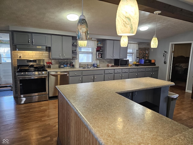 kitchen with dark wood-type flooring, hanging light fixtures, stainless steel appliances, and sink