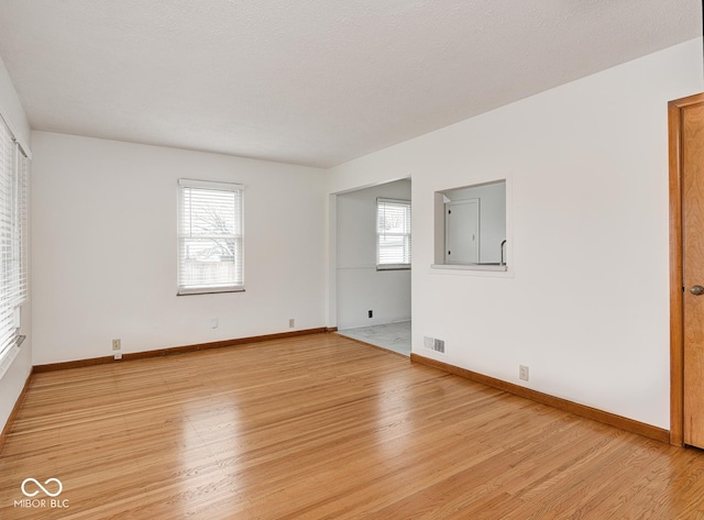 unfurnished room with a textured ceiling and light hardwood / wood-style flooring