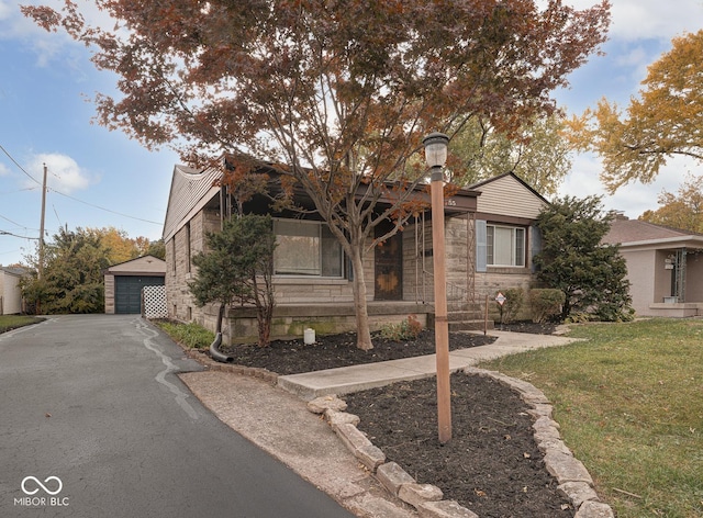 view of property hidden behind natural elements featuring a garage, an outdoor structure, and a front lawn