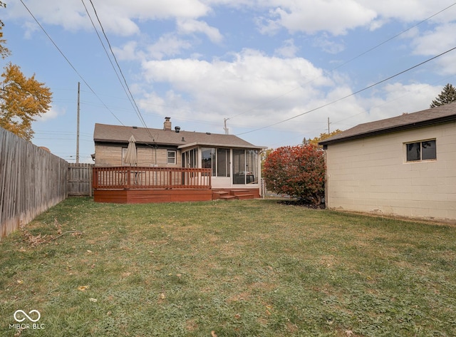 back of house featuring a wooden deck, a lawn, and a sunroom