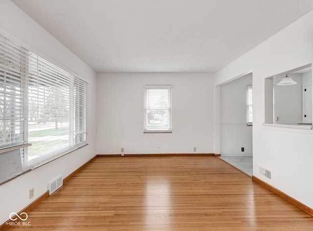 spare room featuring a textured ceiling and light wood-type flooring