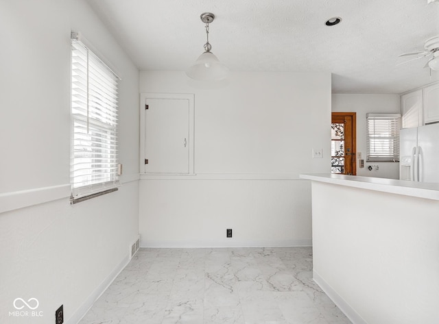 interior space featuring ceiling fan, a healthy amount of sunlight, and a textured ceiling