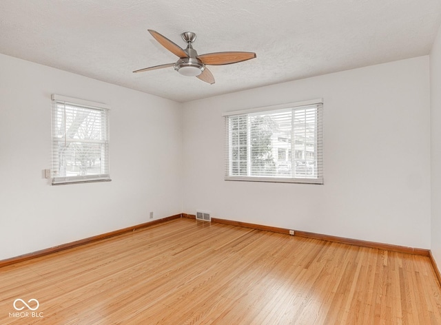 empty room with wood-type flooring, a textured ceiling, and a wealth of natural light