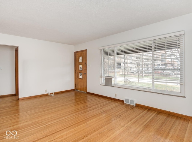 spare room with a textured ceiling and light hardwood / wood-style flooring